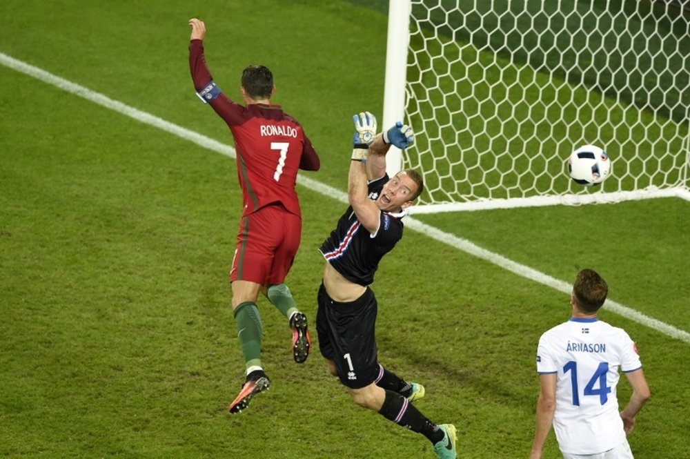 Portugals forward Cristiano Ronaldo (L) jumps for the ball with Icelands goalkeeper Hannes Halldorsson during the Euro 2016 match in Saint-Etienne on June 14, 2016