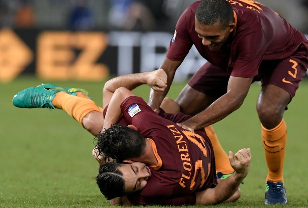 Romas defender from Greece Kostas Manolas (bottom) celebrates with teammates Alessandro Florenzi and Juan Jesus after scoring on October 2, 2016