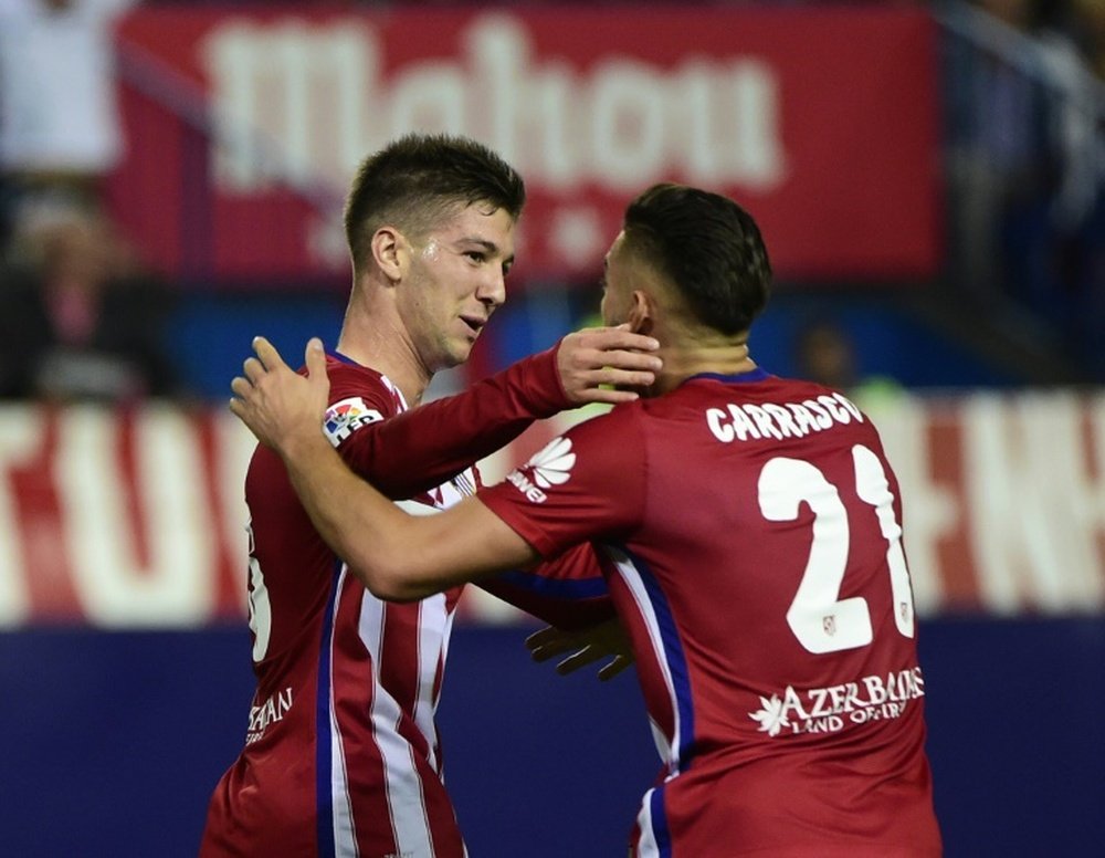Atletico Madrids forward Luciano Vietto (L) celebrates with midfielder Yannick Ferreira Carrasco after scoring during a Spanish league football match against Real Madrid at the Vicente Calderon stadium in Madrid on October 4, 2015