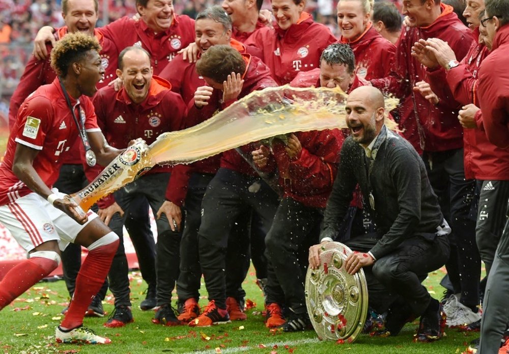 Bayern Munichs head coach Pep Guardiola (R) is doused in beer by Bayern Munichs midfielder David Alaba (L) as they celebrate their Bundesliga title after the German first division Bundesliga football match in Munich, Germany, on May 14, 2016