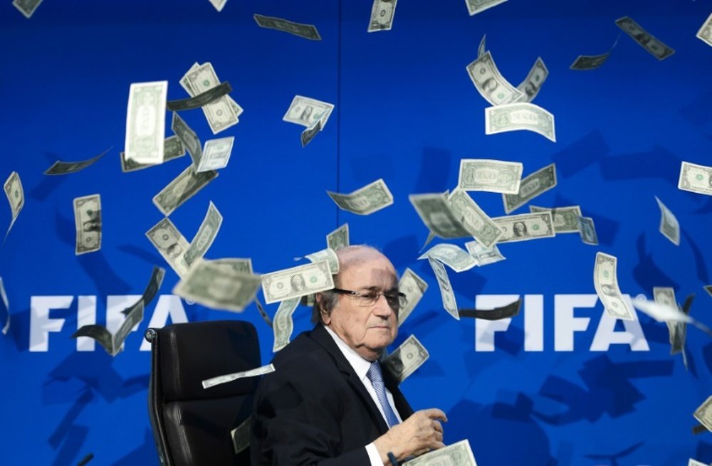 Fake dollar notes thrown by a British comedian flies around FIFA president Sepp Blatter during a press conference at the FIFA headquarters in Zurich on July 20, 2015