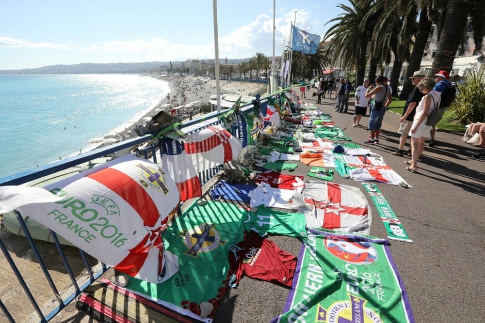 People stand next to tributes for a Northern Ireland fan who died during the Euro 2016 football tournament in Nice