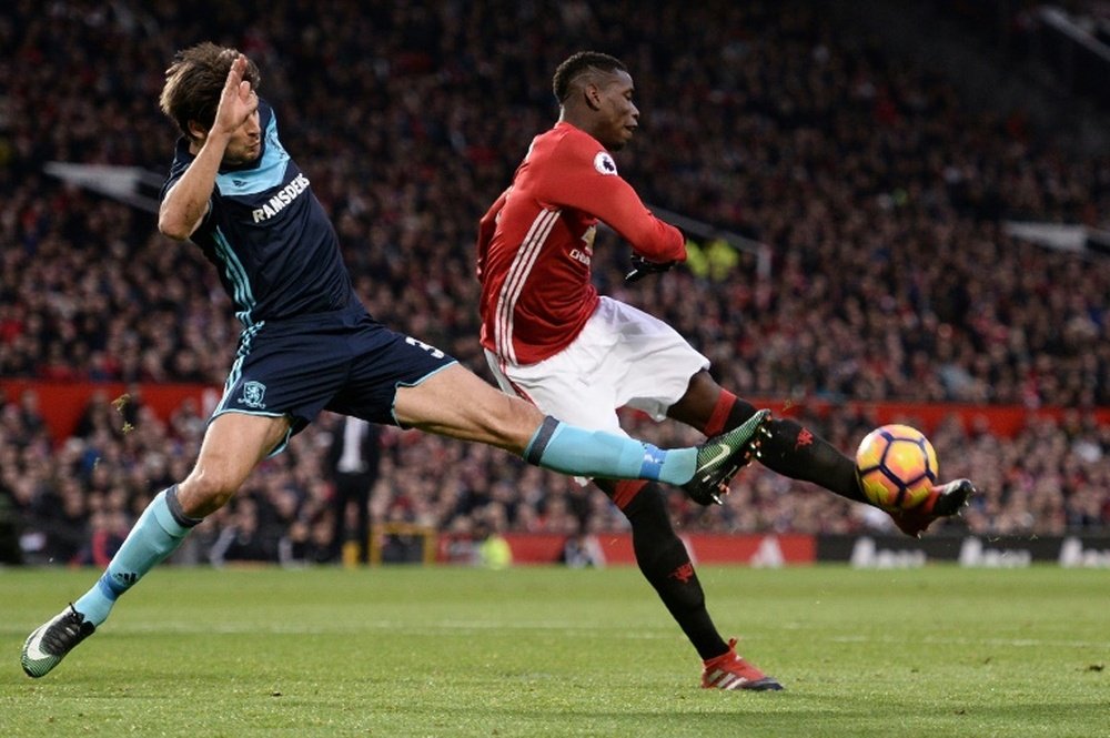 Manchester Uniteds midfielder Paul Pogba (R) attemps to shoot past Middlesbroughs defender George Friend during the English Premier League football match at Old Trafford in Manchester, north west England, on December 31, 2016