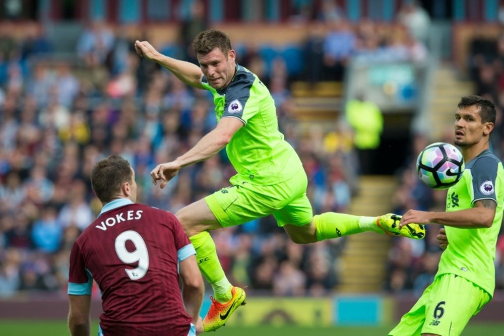 Liverpools James Milner jumps for the ball as Burnleys Sam Vokes and Liverpools Dejan Lovren look on during their English Premier League match, at Turf Moor in Burnley, on August 20, 2016