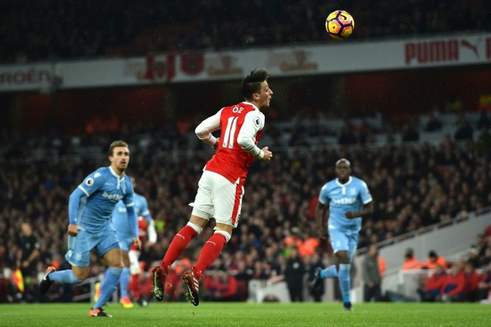 Arsenals Mesut Ozil (C) heads the ball to score a goal during their English Premier League match against Stoke City, at the Emirates Stadium in London, on December 10, 2016