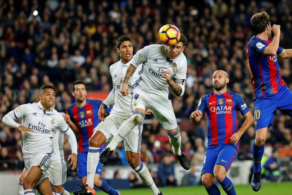 Real Madrids defender Sergio Ramos (C) heads a ball to score the equalizer past Real Madrids Raphael Varane (3rdL) and Barcelonas defender Javier Mascherano (R) during the Spanish league football match on December 3, 2016