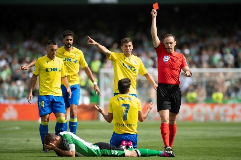 Spanish referee Guillermo Cuadra Fernandez (R) shows a red card to Real Betis midfielder Sergio Canales