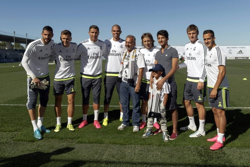 Osama Abdul Mohsen (C) and his sons Mohammad (3R) and Zaid (front) pose with (from L) Real Madrids Kiko Casilla, Denis Cheryshev, Cristiano Ronaldo, Pepe, Luka Modric, Toni Kroos and Lucas at the training ground in Madrid on September 18, 2015
