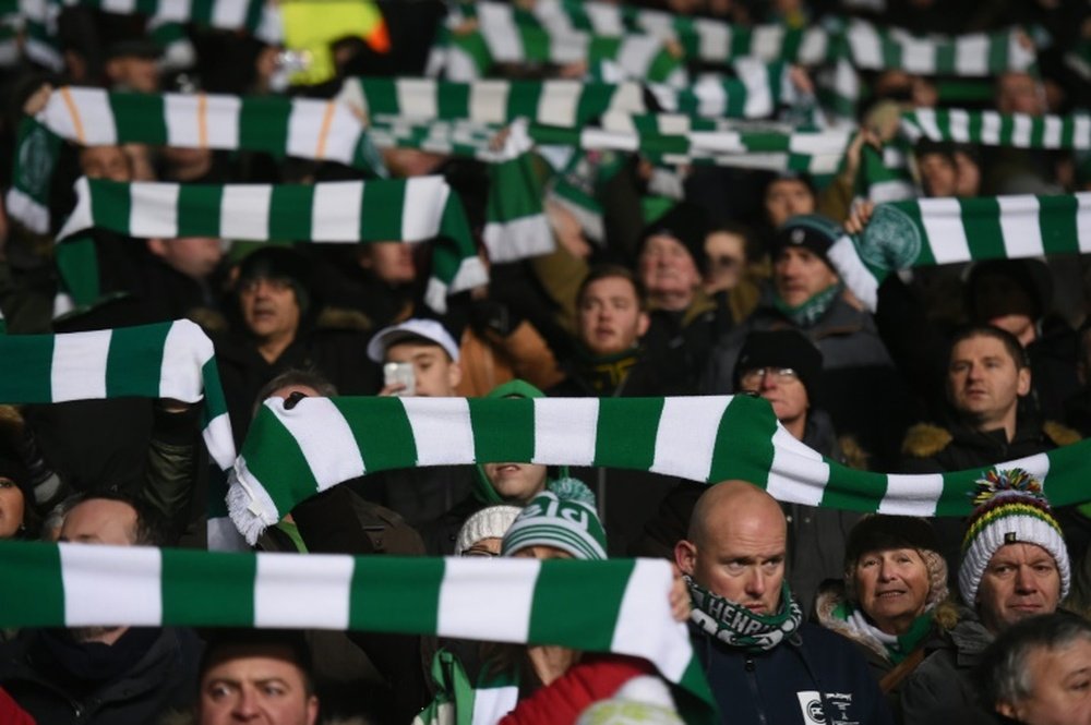 Celtic fans hold up team scarves in Glasgow. AFP