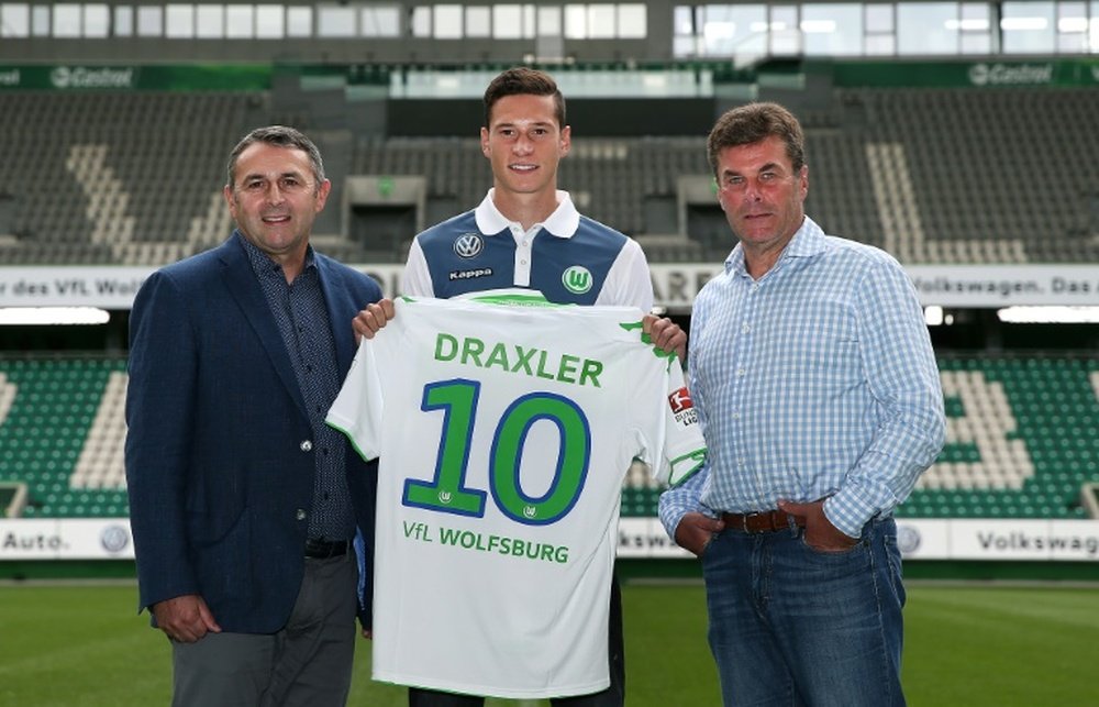 Newly signed midfielder Julian Draxler (C), poses for a picture with Wolfsburgs sporting director Klaus Allofs (L) and Wolfsburg coach Dieter Hecking at Volkswagen-Arena in Wolfsburg, central Germany, on September 1, 2015