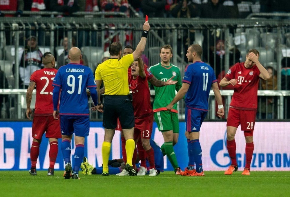 Referree Jonas Eriksson shows a red card to Bayern Munichs Holger Badstuber (R) during a UEFA Champions League match against Olympiakos on November 24, 2015 at the Allianz Arena in Munich, southern Germany