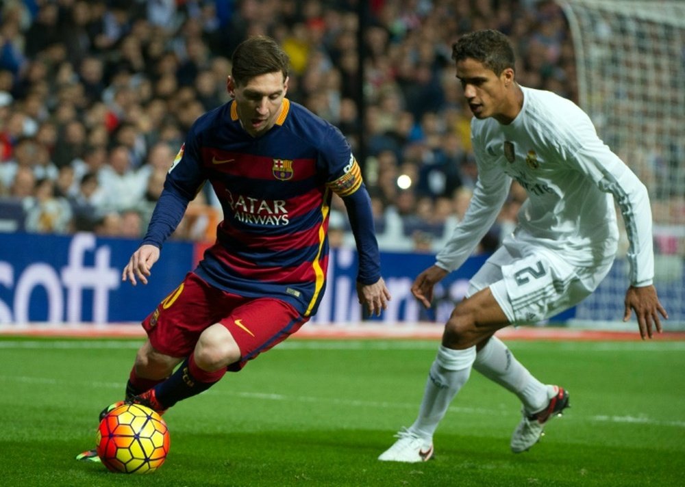 Barcelonas Lionel Messi (L) slips past Real Madrids Raphael Varane during their Spanish league Clasico match at the Santiago Bernabeu stadium in Madrid on November 21, 2015