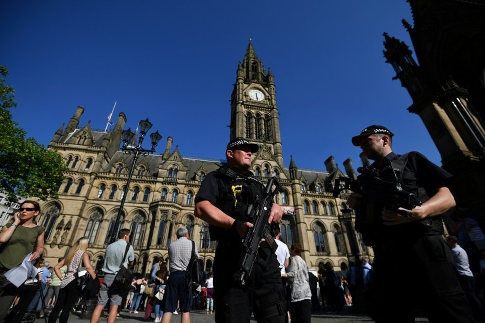 Armed police stand guard in front of the Town Hall in Albert Square
