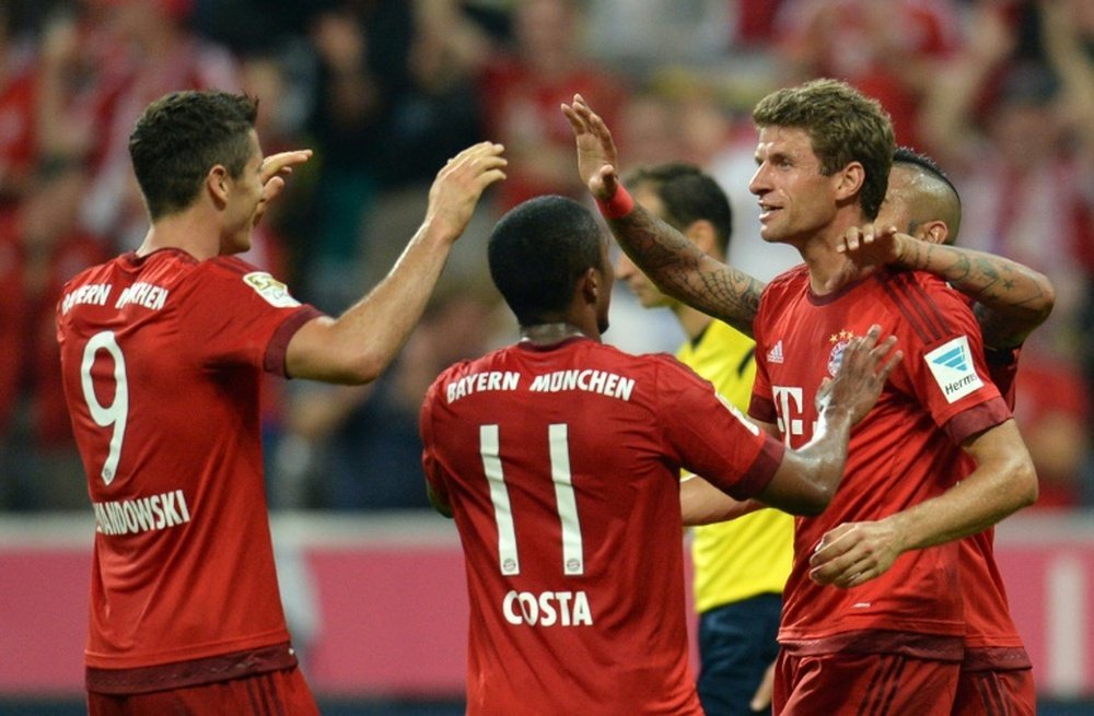 Bayern Munichs Thomas Mueller (R) celebrates scoring on of two goals in his sides 5-0 trouncing of Hamburg in the first game of the Bundesliga season on August 14, 2015