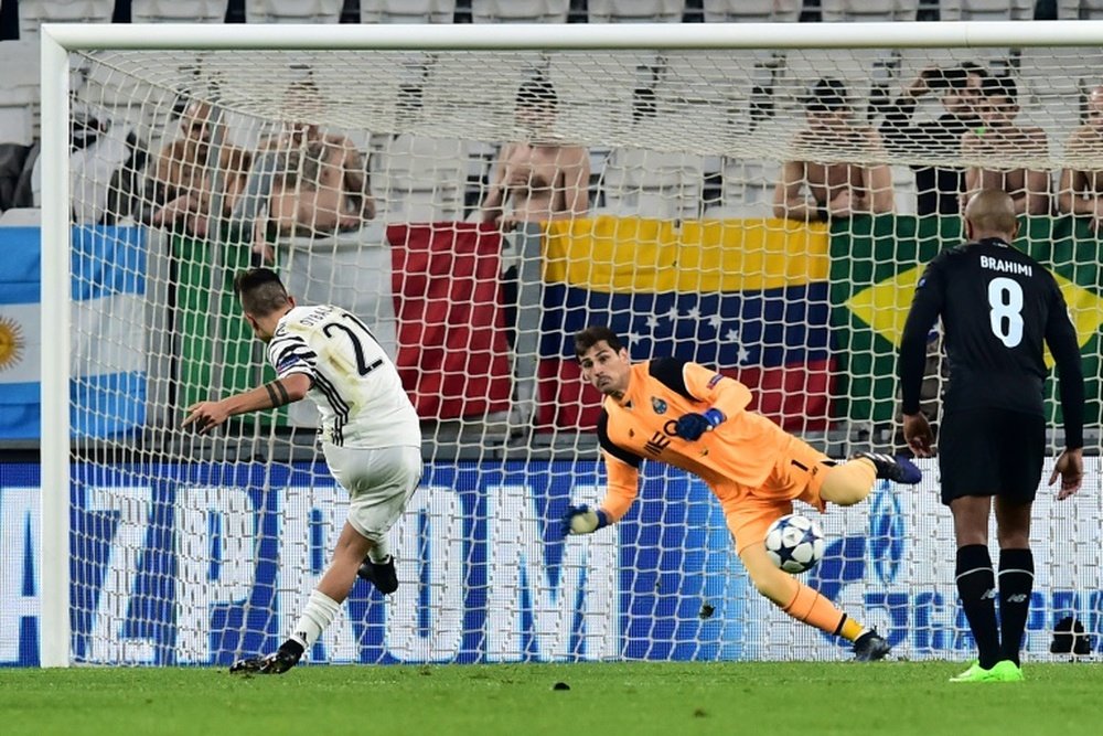 Juventus forward Paulo Dybala (L) scores a penalty against Portos goalkeeper Iker Casillas