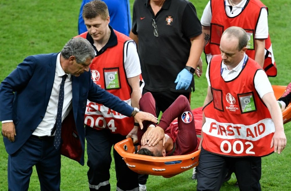 Portugals forward Cristiano Ronaldo is comforted by Portugals coach Fernando Santos as he is carried on a stretcher off the pitch by team medics after an injury following a clash with Frances forward Dimitri Payet during the Euro 2016 final