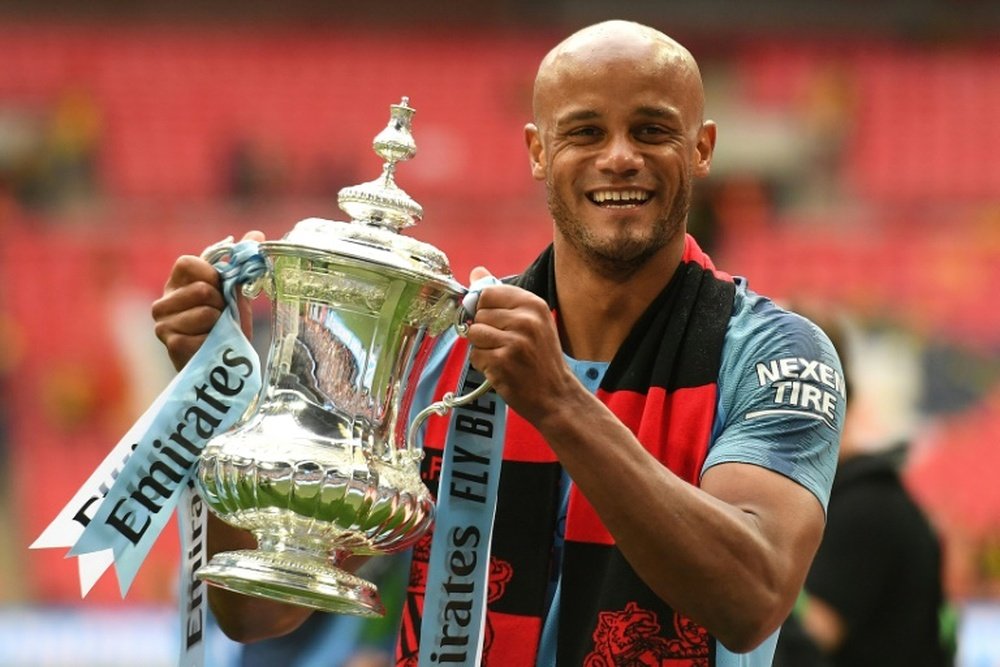 Vincent Kompany with the third of his 3 trophies this season. AFP