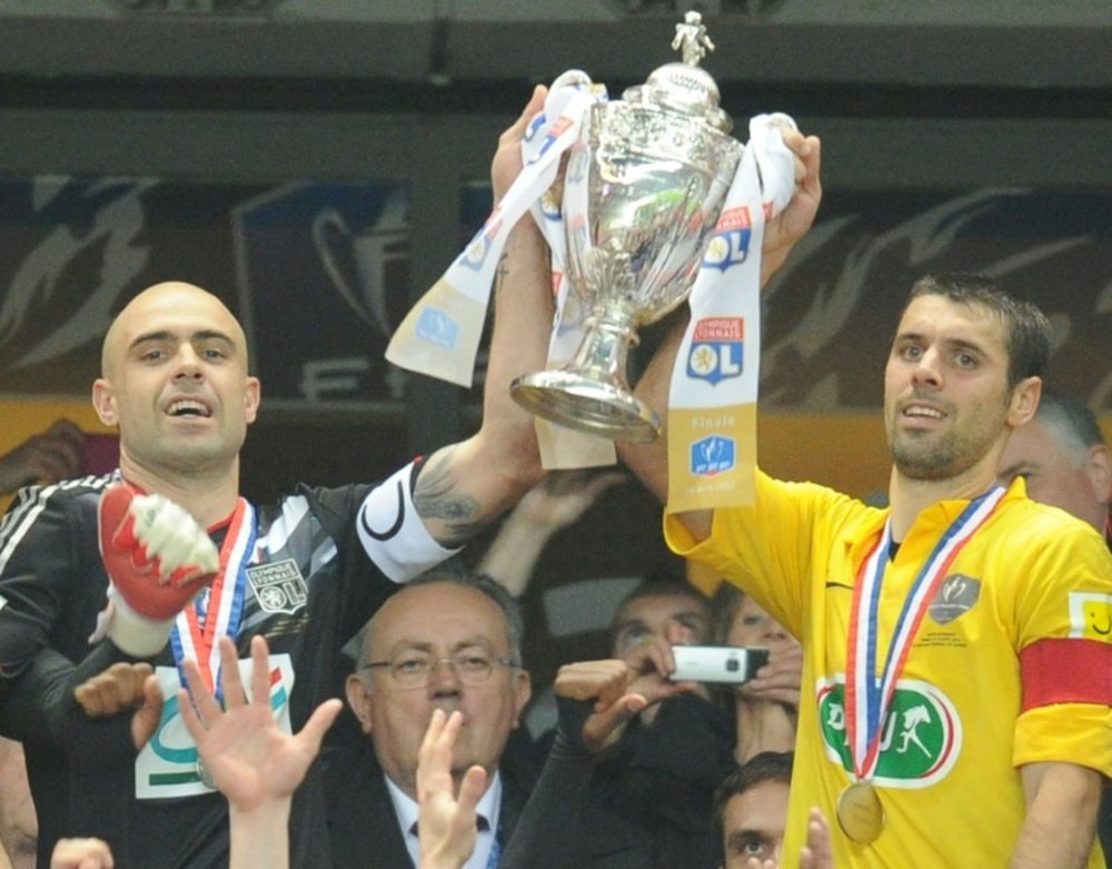 Les capitaines de Lyon et de Quevilly  brandissent ensemble le trophée de la Coupe de France. AFP