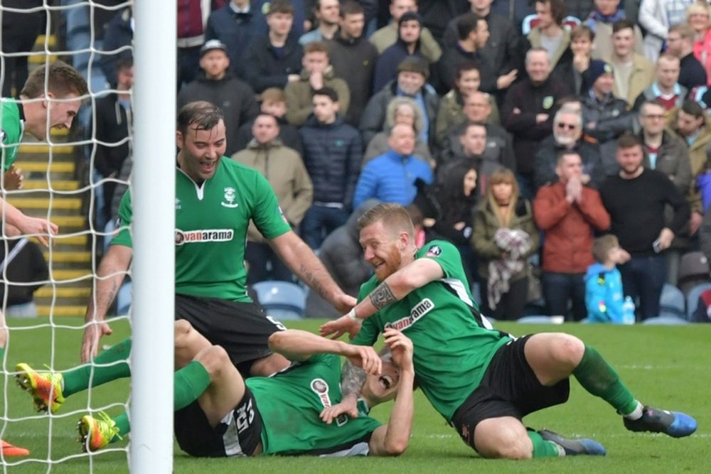 Sean Raggett, en el centro, en el suelo, celebrando un gol, podría fichar por el West Ham. AFP/Archi