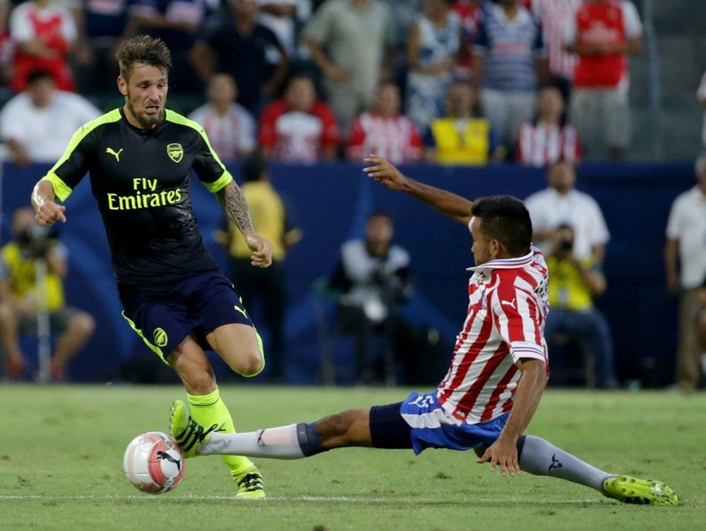 Le défenseur d'Arsenal Mathieu Debuchy (g) est taclé par Hedgardo Marin de Chivas. AFP