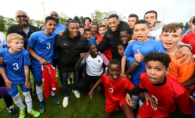 Lattaquant Anthony Martial (c-d) et le défenseur Patrice Evra (c-g) , tous deux en équipe de France, posent avec de jeunes footballeurs des Ullis (Essonne), le 23 mai 2016
