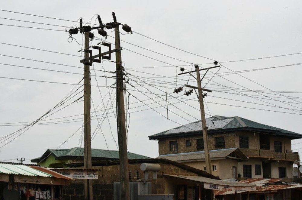 Poteaux électriques, transformateurs et panneaux solaires surplombent des immeubles de Lagos. AFP