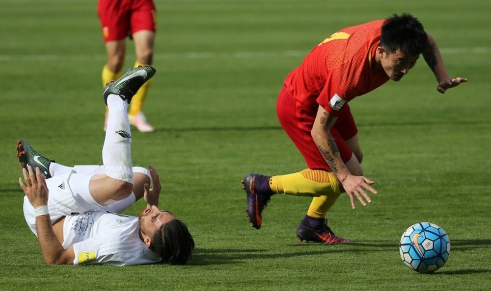 Le Chinois  Zhipeng trébuche sur l'Iranien Jahanbakhsh au cours du match de qualification. AFP