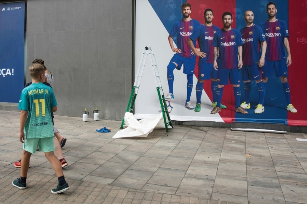Un jeune supporter de Neymar Jr s'attarde sur le nouveau poster publicitaire du Barça. AFP