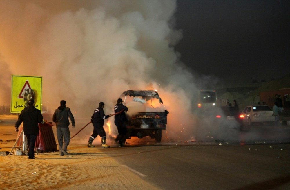 Des pompiers saffairent autour dun véhicule en feu après des incidents près dun stade au Caire. AFP