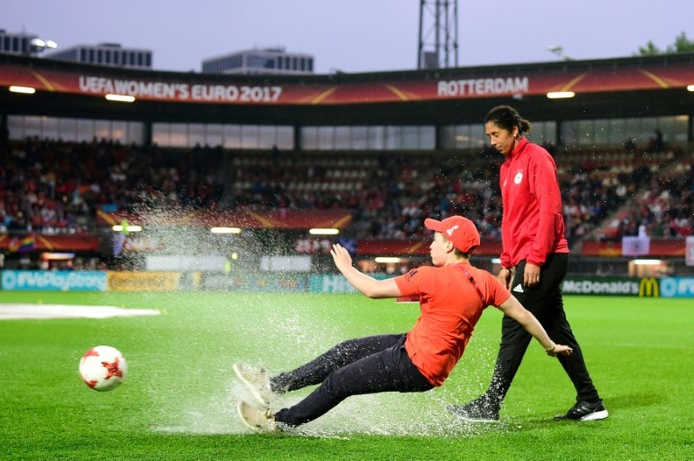 Un jeune volontaire de l'Euro glisse dans une flaque d'eau. AFP