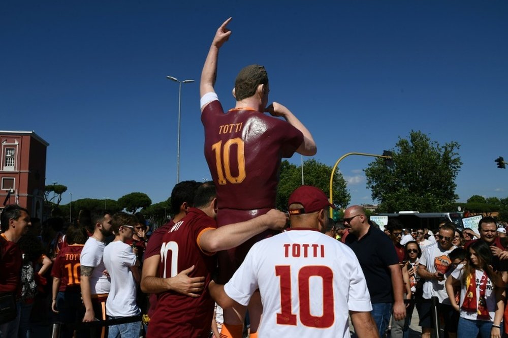 Des supporters de l'AS Rome posent à côté dune statue de Francesco Totti. AFP