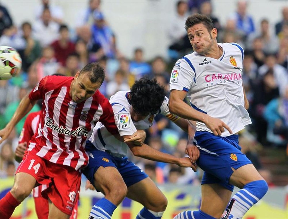 El defensa del Real Zaragoza Rubén González (c) disputa un balón con el centrocampista del Girona Pablo Íñiguez (i), durante el partido de ida de la primera eliminatoria de la Promoción de ascenso a Primera División que se juega hoy en el estadio de La Romareda. EFE
