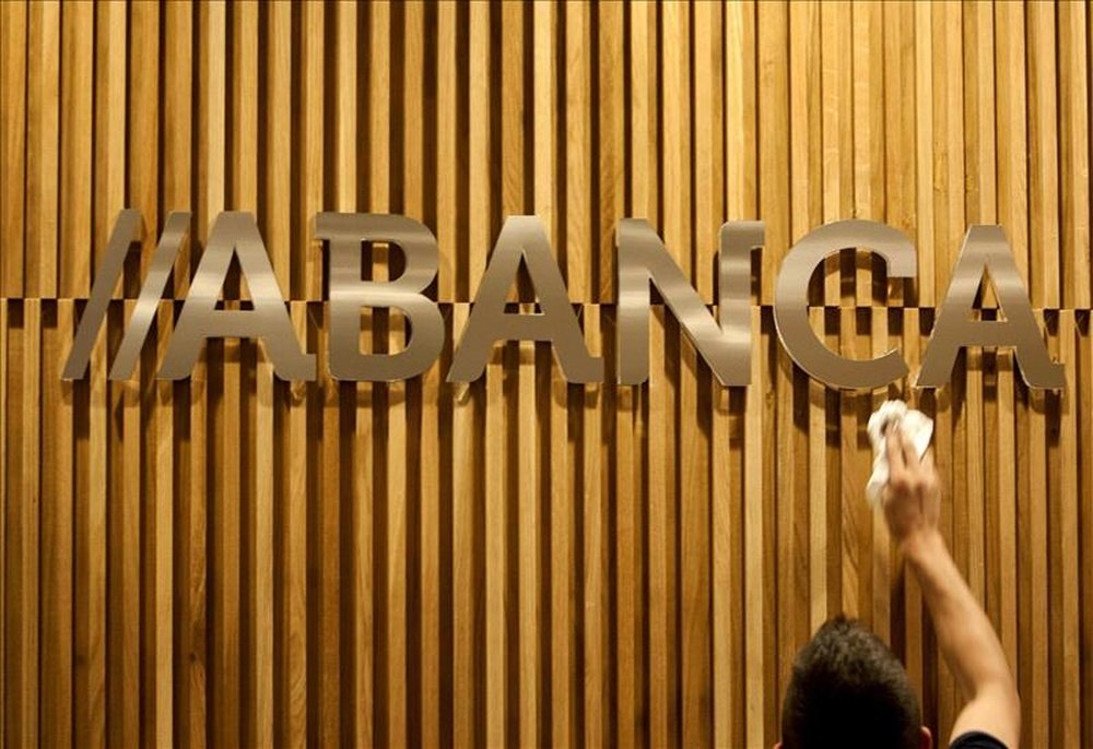 Un operario limpia en una oficina de Santiago de Compostela el logotipo de Abanca. EFE/Archivo 