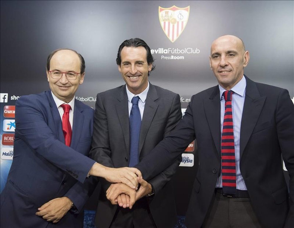 El presidente del Sevilla F.C, José Castro (i), junto al director deportivo, Ramón Rodriguez Monchi (d), estrechan las manos con el entrenador Unay Emery, tras la ampliación de su contrato hasta junio de 2017 con el club de Nervión. EFE