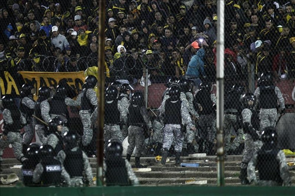 Fotografía tomada el pasado 14 de junio en la que se registró a un grupo de policías al enfrentarse a aficionados de Peñarol, durante la final del torneo Clausura 2015 del fútbol uruguayo, en el estadio Centenario de Montevideo (Uruguay). EFE/Archivo
