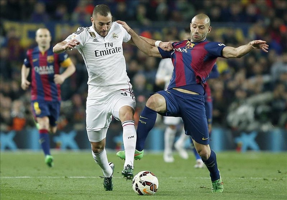 El delantero francés del Real Madrid, Karim Benzema (i), disputa un balón con el defensa argentino del F. C. Barcelona, Javier Mascherano, en el estadio del Camp Nou, Barcelona. EFE/Archivo