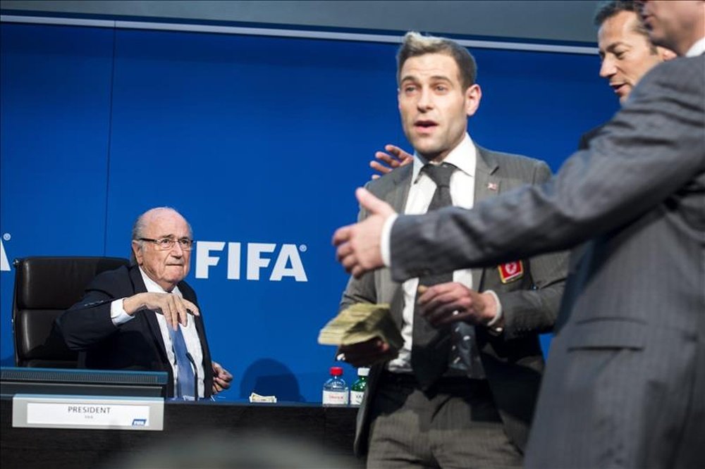 El presidente de la FIFA, Joseph Blatter (i), junto al humorista británico Simon Brodkin (c), quien le lanzó una lluvia de billetes durante una rueda de prensa para presentar los resultados de la reunión del Comité Ejecutivo de la FIFA en su sede de Zúrich, Suiza. EFE