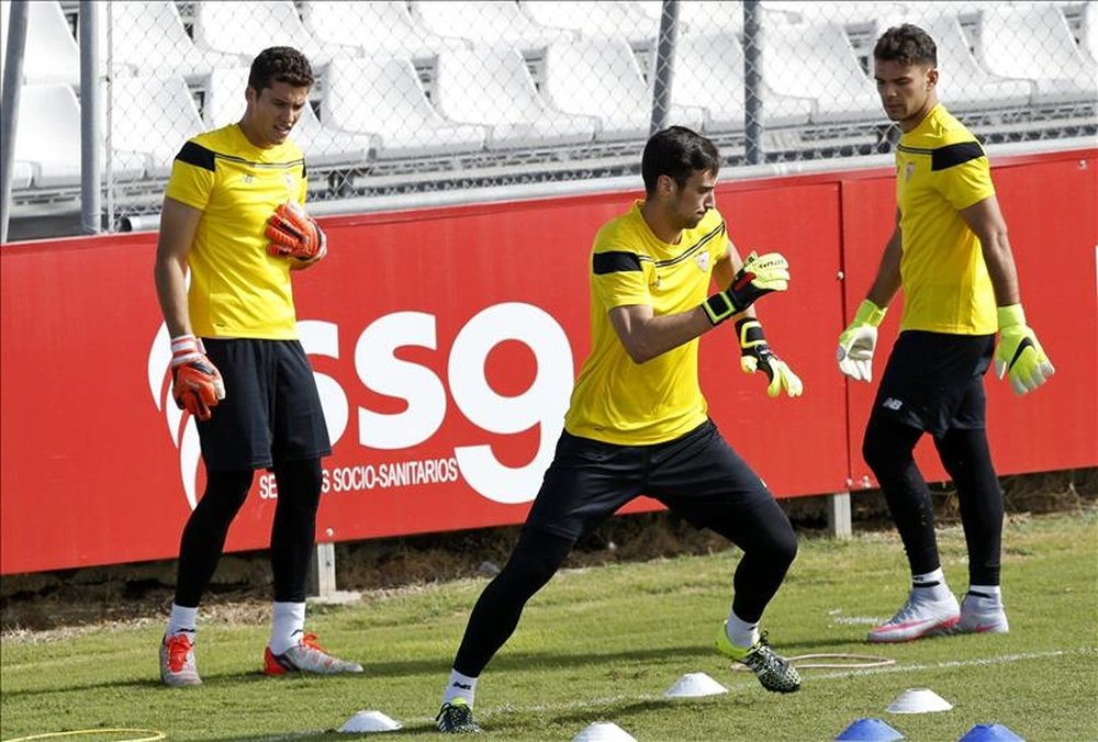 Los porteros del Sevilla, David Soria (i) y Sergio Rico (c), durante el entrenamiento que el equipo ha realizado hoy en la ciudad deportiva previo al primer partido de la fase de grupos que el equipo sevillano disputará mañana ante el Borussia de Mönchengladbach. EFE 
