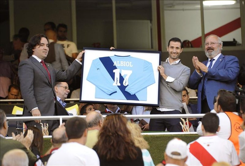 El futbolista Miguel Albiol (2d) recibe de manos del presidente Raúl Martín Presa (i), un cuadro con su camiseta enmarcada y con el número diecisiete a la espalda, durante el homenaje que le ha rendido hoy el Rayo Vallecano, antes del partido frente al Deportivo de la tercera jornada de la Liga de Primera División que se juega en el estadio de Vallecas. EFE
