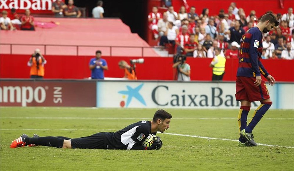 El portero del Sevilla Sergio Rico (i) retiene el balón en el suelo junto al defensa del FC Barcelona Gerard Piqué (d), durante el partido de la séptima jornada de la Liga de Primera División que se jugó en el estadio Ramón Sánchez-Pizjuán. EFE