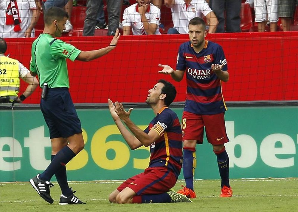 El centrocampista del FC Barcelona Sergio Busquets (c) protesta al árbitro Jesús Gil durante el partido correspondiente a la séptima jornada de Liga que disputaron en el estadio Sánchez Pizjuan. EFE