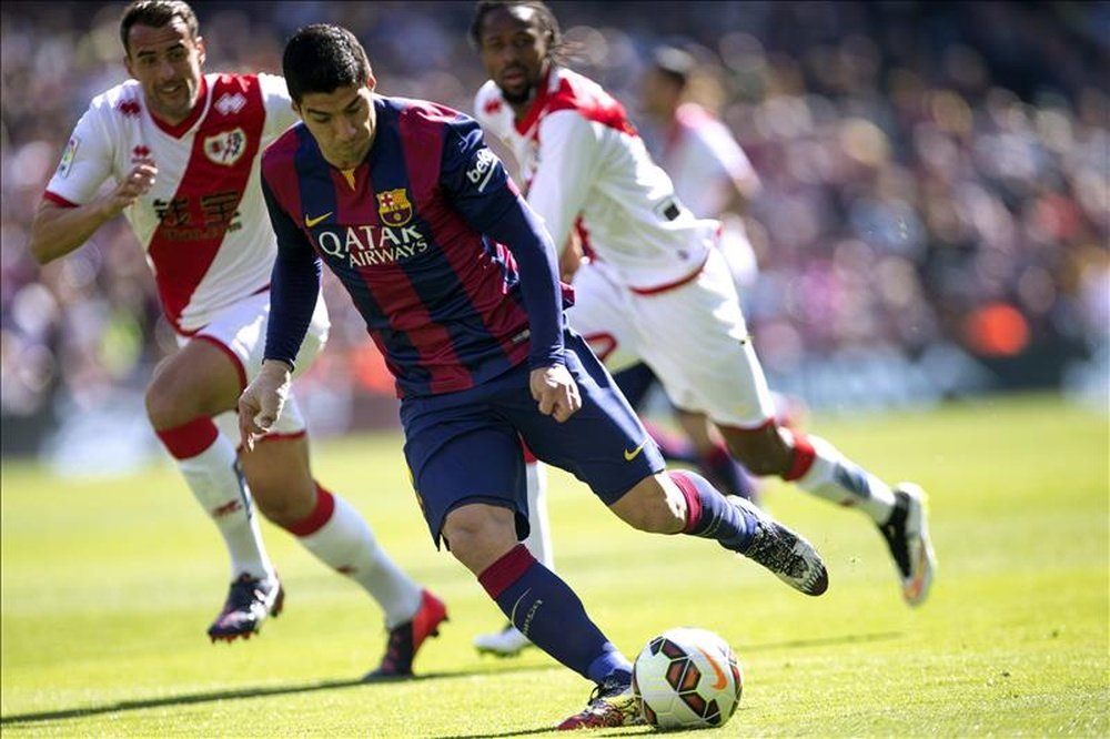 El delantero uruguayo del FC Barcelona, Luis Suárez, controla la pelota ante los defensas del Rayo Vallecano durante un partido de la pasada liga. EFE/Archivo