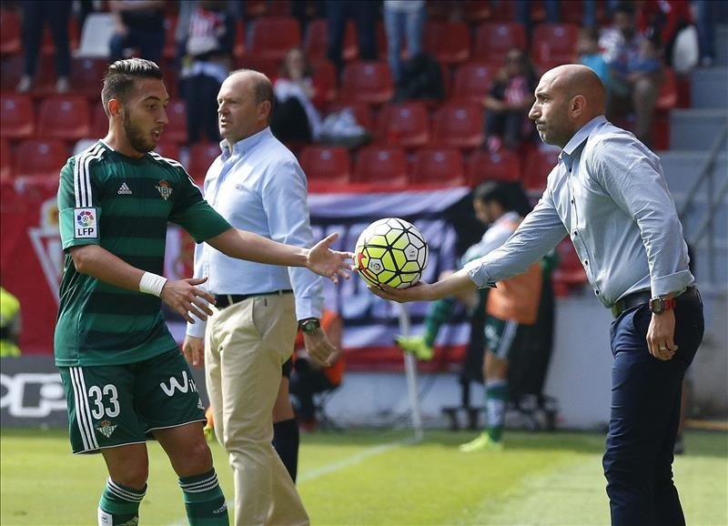 El entrenador del Sporting Abelardo Fernández (d) entrega el balón al defensa del Real Betis Francisco Varela (i). EFE/Archivo