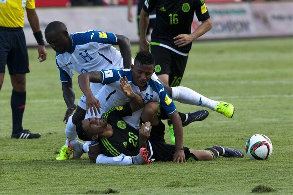 En la imagen, el jugador mexicano Javier Aquino (abajo) disputa el balón con los hondureños Wilmer Crisantos (i) y Luis Garrido (c) durante un partido por las eliminatorias de la Copa Mundial de la FIFA Rusia 2018, en el estadio Olímpico de San Pedro Sula (Honduras). EFE/Archivo