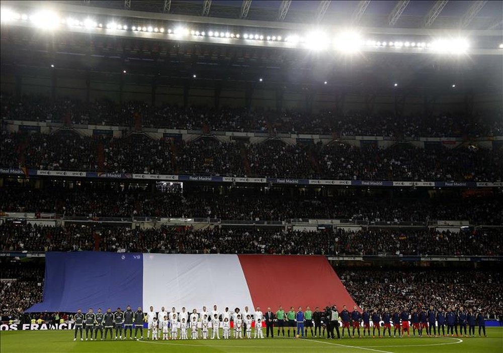Los jugadores del Real Madrid y del FC Barcelona se suman a un homenaje a las víctimas de los atentados terroristas del pasado 13 de noviembre en París, con La Marsellesa sonando a piano por la megafonía y una bandera de Francia de grandes dimensiones ocupa gran parte del lateral. EFE