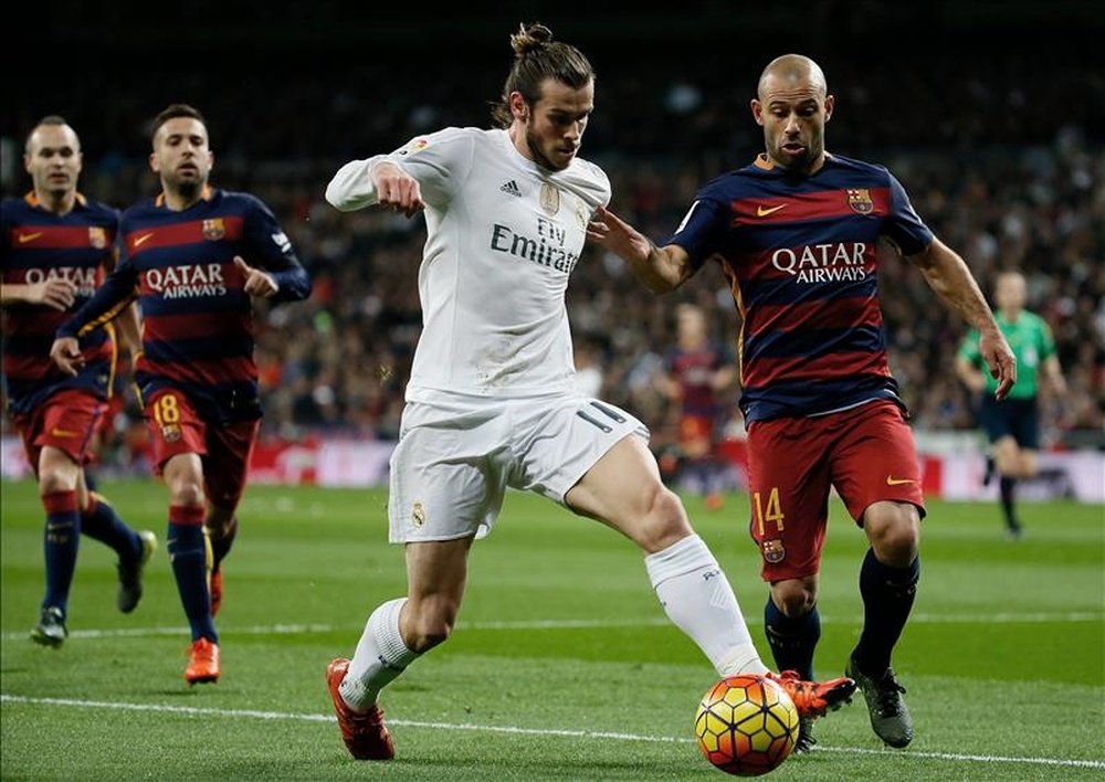 El delantero galés del Real Madrid Gareth Bale (i) pelea un balón con el argentino Javier Mascherano, del FC Barcelona, durante el partido de Liga de Primera División, de la jornada 12º, que les enfrentó este sábado en el Estadio Santiago Bernabéu, en Madrid. EFE