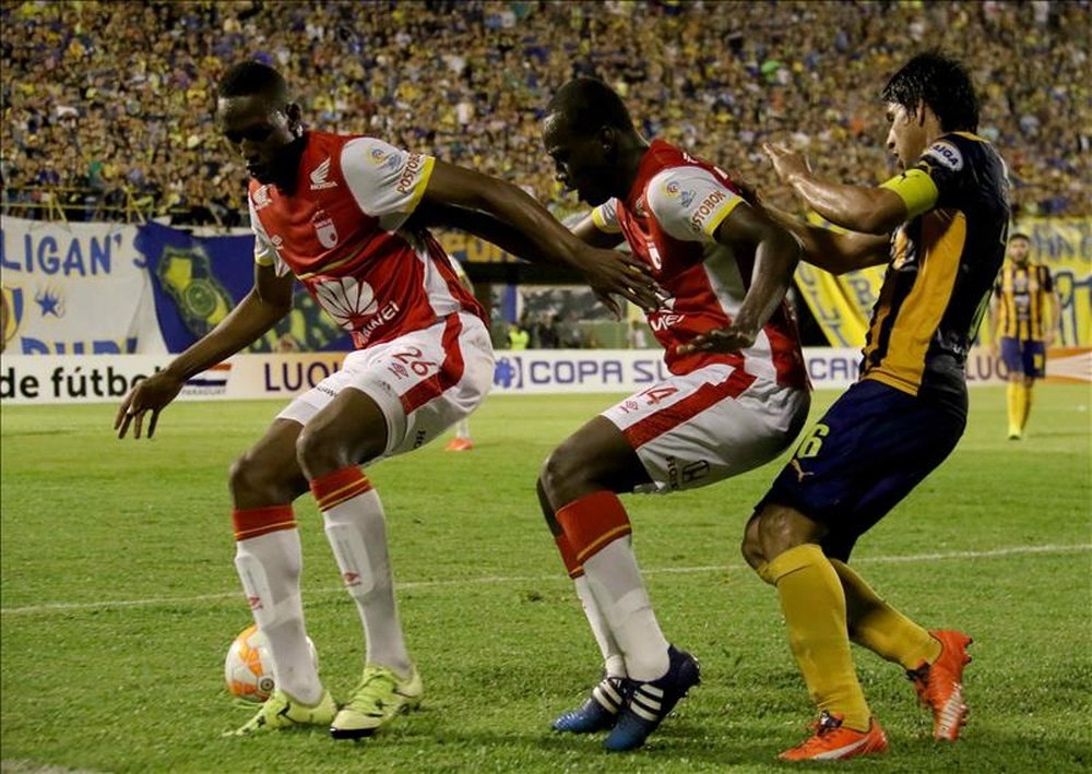 Los jugadores Yerri Mina (i) y Baldomero Perlaza (c) del Independiente Santa Fe de Colombia disputan el balón con Luis Miño (d) del Sportivo Luqueño de Paraguay. EFE