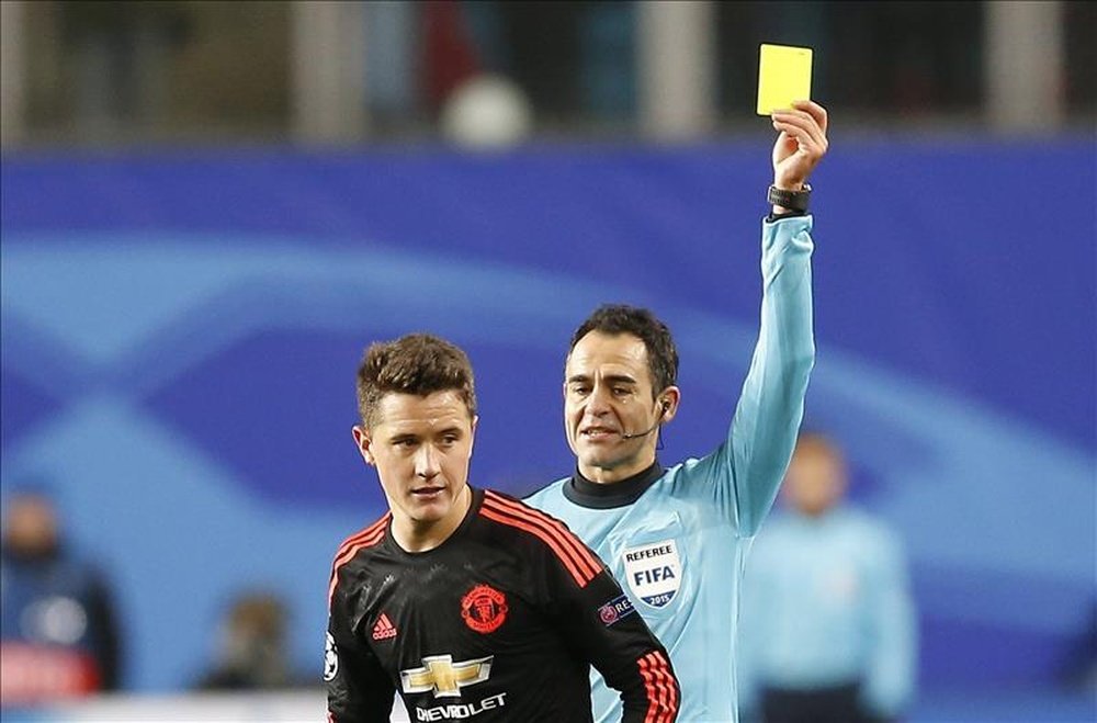 El árbitro español Carlos Velasco Carballo (d) muestra una tarjeta amarilla a Ander Herrera (i) del Manchester United. EFE/Archivo