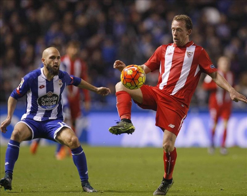 El centrocampista danés del Sevilla, Michael Krohn-Dehli (d), intenta controlar el balón ante el defensa del Deportivo, Laureano Sanabria Laure, durante el encuentro correspondiente a la decimocuarta jornada de primera división, que disputaron en el estadio de Riazor, en La Coruña. EFE