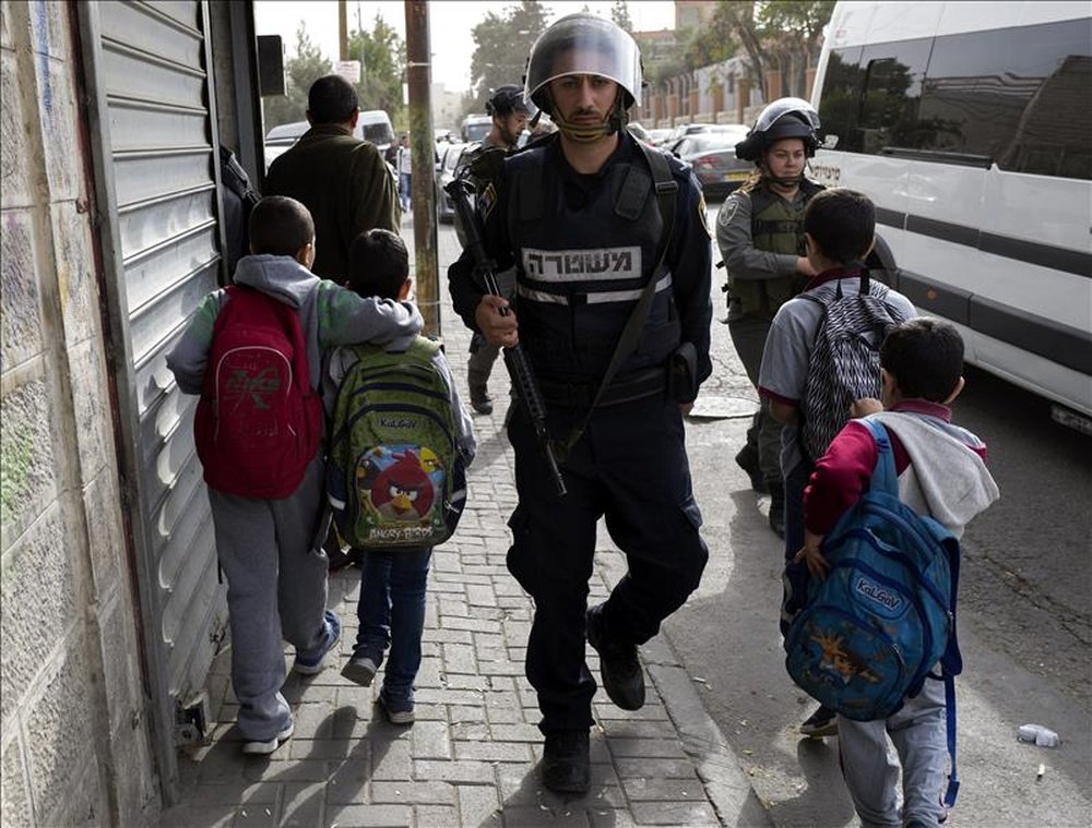 Varios niños caminan junto a agentes de la policía israelí de fronteras en la zona del Monte de los Olivos en Jerusalén. EFE/Archivo